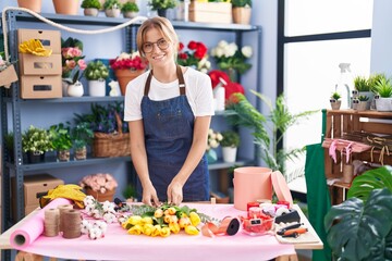 Young blonde girl florist prepare bouquet of flowers at florist