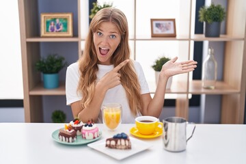 Obraz na płótnie Canvas Young caucasian woman eating pastries t for breakfast amazed and smiling to the camera while presenting with hand and pointing with finger.