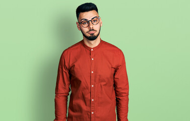 Young hispanic man with beard wearing business shirt and glasses depressed and worry for distress, crying angry and afraid. sad expression.