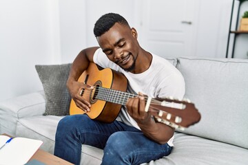 Young african american man smiling confident playing guitar at home - Powered by Adobe