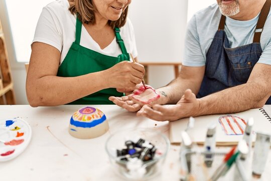 Artist couple painting palm hands at art studio.
