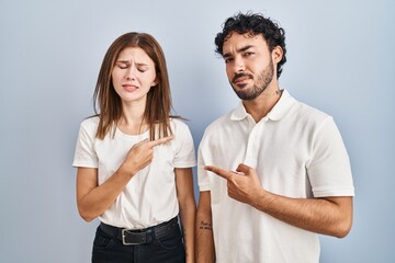 Young couple wearing casual clothes standing together pointing aside worried and nervous with forefinger, concerned and surprised expression