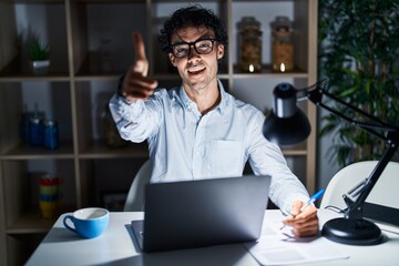 Hispanic man working at the office at night pointing fingers to camera with happy and funny face. good energy and vibes.