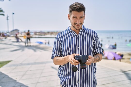 Young handsome man using dslr photography camera by the sea