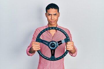 Young african american guy holding steering wheel skeptic and nervous, frowning upset because of problem. negative person.
