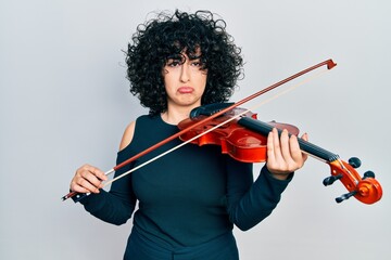 Young middle east woman playing violin depressed and worry for distress, crying angry and afraid....