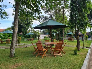 garden in summer with patio, wooden garden furniture and a parasol or sun umbrella