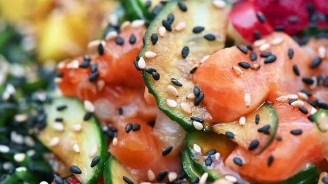 Close view of poke with vegetables, seeds and seafood in a bowl