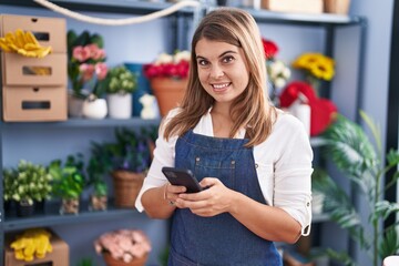 Young woman florist smiling confident using smartphone at florist