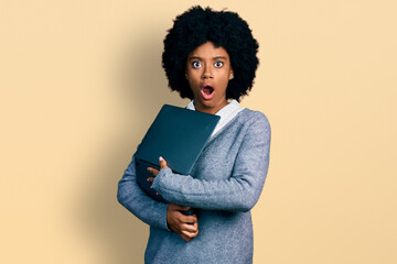 Young african american woman working using computer laptop afraid and shocked with surprise and...