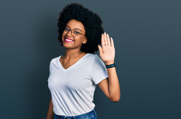 Young african american woman wearing casual white t shirt waiving saying hello happy and smiling, friendly welcome gesture