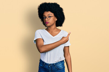 Young african american woman wearing casual white t shirt pointing with hand finger to the side showing advertisement, serious and calm face