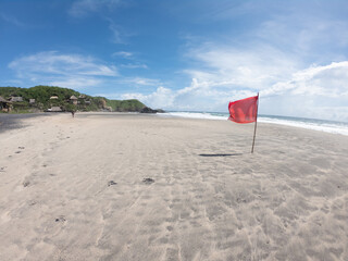 Red flag on Mexican beach with clear blue sky.