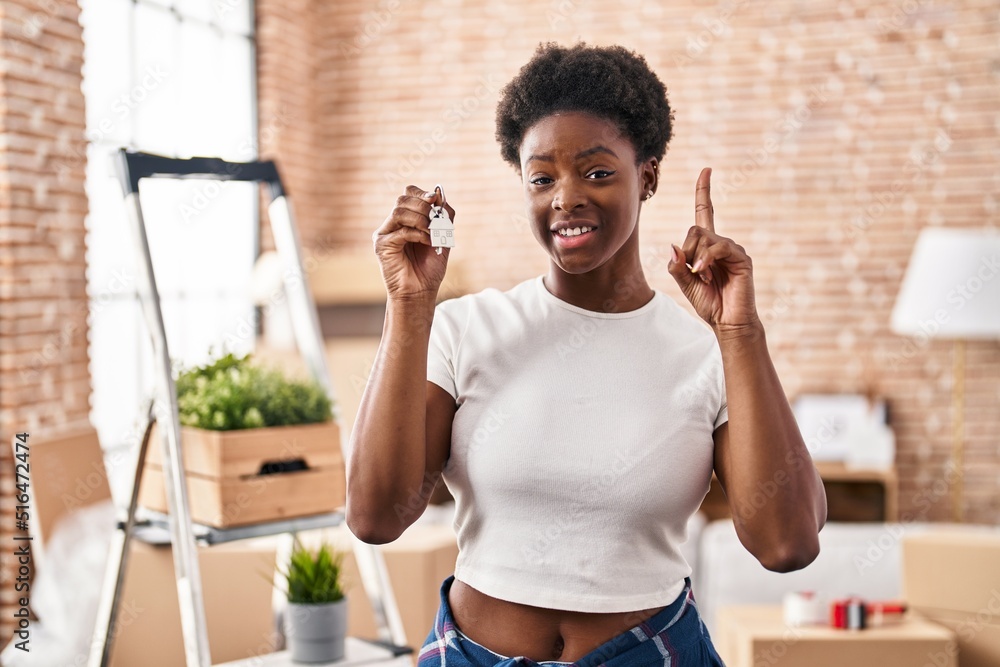 Sticker African american woman holding keys of new home surprised with an idea or question pointing finger with happy face, number one