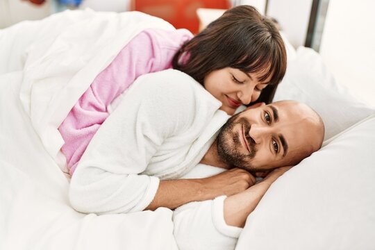 Young hispanic couple smiling happy lying on the bed at bedroom.