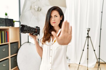 Beautiful caucasian woman working as photographer at photography studio doing stop sing with palm...