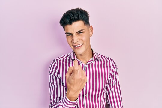 Young hispanic man wearing casual clothes beckoning come here gesture with hand inviting welcoming happy and smiling