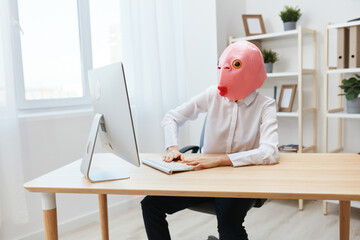 Focused funny crazy businesswoman worker freelancer in pink fish mask work on computer online pondering or making decision thinking of problem solution in light modern office. Copy space
