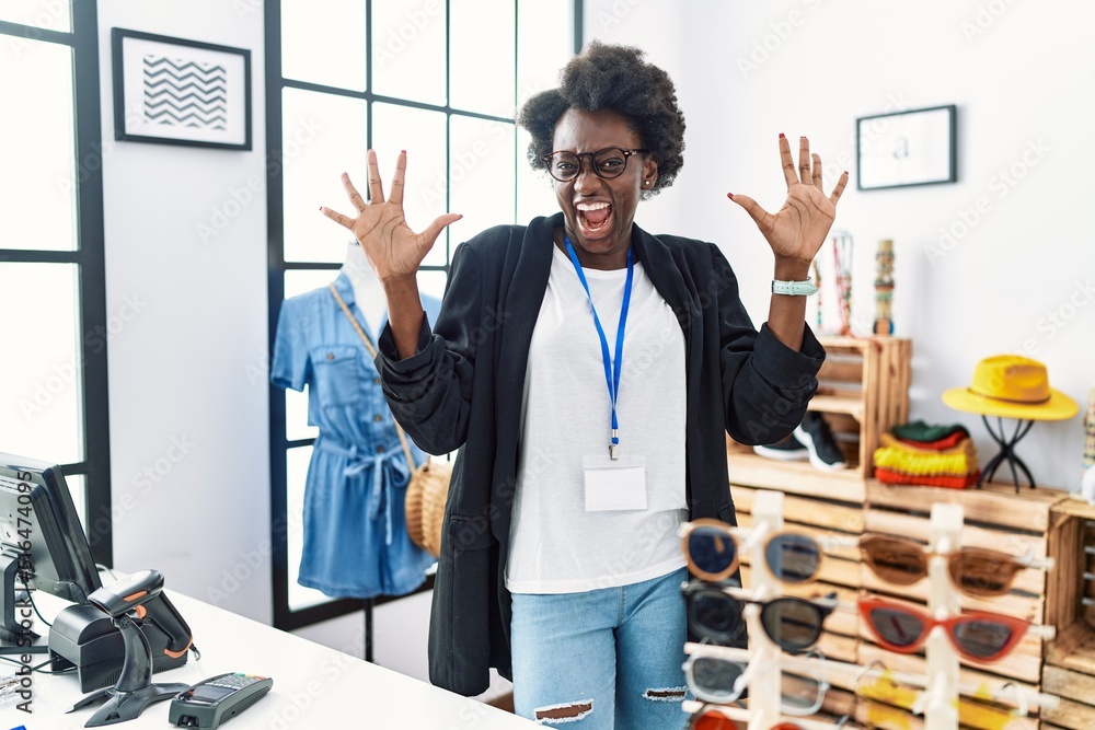 Sticker african young woman working as manager at retail boutique showing and pointing up with fingers numbe