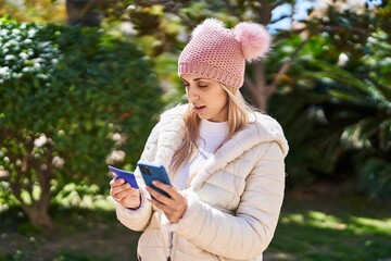 Young woman using smartphone and credit card at park