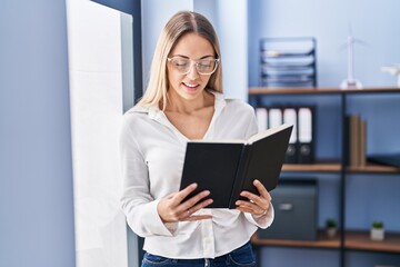 Young woman business worker reading book at office