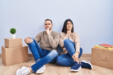 Young couple moving to a new home thinking worried about a question, concerned and nervous with...