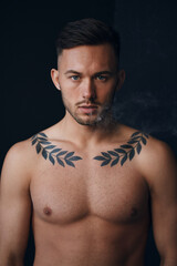 Fototapeta premium Modelling snapshots. Pensive serious tanned attractive handsome naked man thinking looks at camera to you smoking posing isolated in black studio background. Fashion offer. Copy space for ad. Closeup