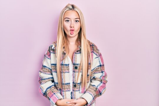 Young blonde girl wearing casual clothes making fish face with lips, crazy and comical gesture. funny expression.