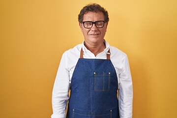 Middle age hispanic man wearing professional cook apron winking looking at the camera with sexy expression, cheerful and happy face.