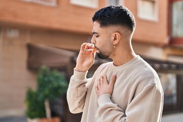 Young arab man smoking with relaxed expression at street