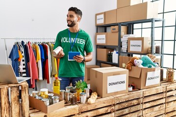 Young arab man wearing volunteer uniform using touchpad at charity center