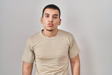 Young arab man wearing casual t shirt looking at the camera blowing a kiss on air being lovely and sexy. love expression.