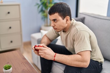 Young man playing video game sitting on sofa at home