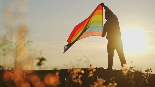 Silhouette with the gay rainbow flag on a mountain top