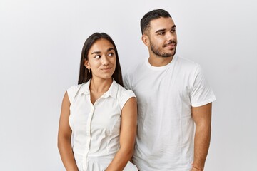 Obraz premium Young interracial couple standing together in love over isolated background smiling looking to the side and staring away thinking.