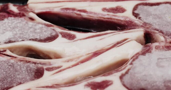 Close-up detail Front view move camera - Time-Lapse Ice flakes on frozen lamb raw packaged, Food concept.