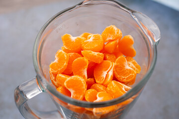 Trozos de Mandarina en una licuadora con fondo azul. Concepto de alimentos.