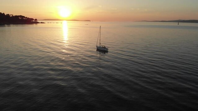 Aerial of a peaceful maritime sailing dream.  Small yacht basks in the final warm summer Spanish sunlight near Bueu beach, Galicia, Spain