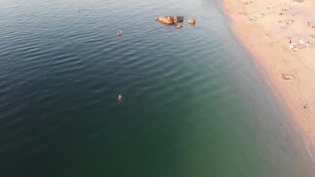 Relaxing day at Tuia Bueu beach in Galicia, Spain.  Turquoise waters, beachgoers, and rugged natural coastline make for an unforgettable Galician weekend