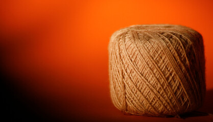 Close up ball of wool thread. Yarn roll. Yarn threads in orange background with copy space