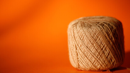 Close up ball of wool thread. Yarn roll. Yarn threads in orange background with copy space