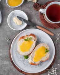 Quick breakfast, bread with butter and lemon cream. Shot on a concrete table in vintage style.