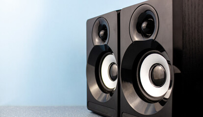 Black glossy music speakers on a blue background with place for text.Music speakers concept.