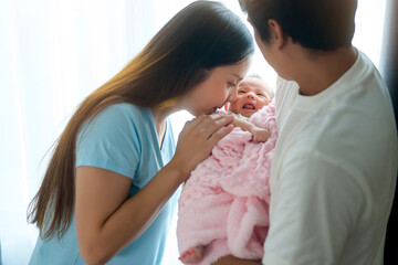 Smiling young mother and father with a new born baby, family and love concept