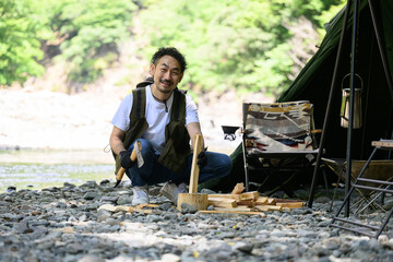 ソロキャンプで薪割りをする人　ベテラン