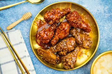 Deep fried chicken wings or barbecue sprinkled with white sesame on golden plate.