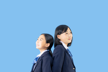背中合わせに立つ制服を着た二人の少女　女子中学生