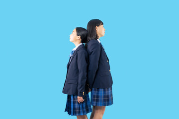 背中合わせに立つ制服を着た二人の少女　女子中学生