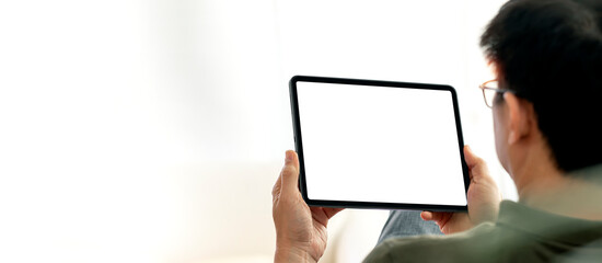 Man using digital tablet sitting at home, mock up blank screen for product display. - Powered by Adobe