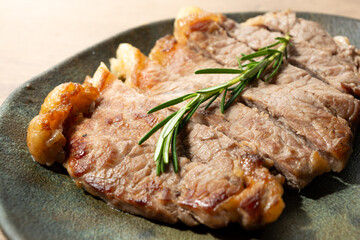 delicious roast beef, on a black plate and wooden surface, with a sprig of thyme on top. copy space.